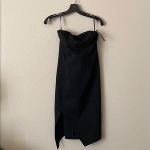 Black body-con cocktail dress with a leg slit.